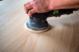 An electric sander sanding down a kitchen door